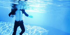 ein Mann im Anzug unter Wasser - nur sein Kopf ist nicht zu sehen