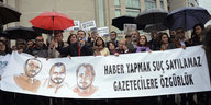 Eine Menschenmenge, manche halten Regenschirme, andere ein Plakat mit der türkischen Aufschrift „Journalismus ist kein Verbrechen - Journalisten befreien“