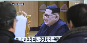 Menschen schauen auf einen Bildschirm, auf dem Kim Jong Un zu sehen ist