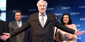 Ein Mann, Horst Seehofer, streckt die Arme weit zu beiden Seiten aus, im Hintergrund stehen mehrere Menschen, gut sichtbar ist ein Mann zu seiner linken und seine Frau zu seiner rechten, die ihn anschaut