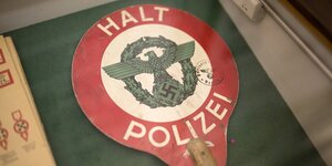 Eine Haltekelle, auf der ein Adler mit Hakenkreuz abgebildet ist, oben und unten steht "Halt Polizei"