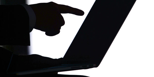 Schattenriss einer Hand, die auf einen Computerbildschirm zeigt