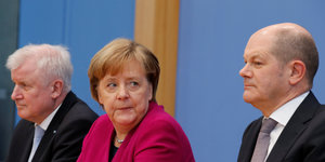 Seehofer, Merkel und Scholz sitzen nebeneinander, Merkel schaut Scholz an