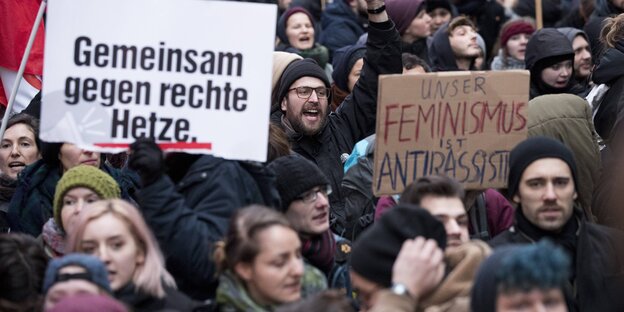 Demonstranten und Demonstrantinnen halten Schilder in die Höhe, auf denen "Gemeinsam gegen rechte Hetze" und "Unser Feminismus ist antirassistisch" steht