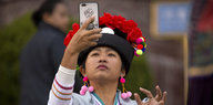 Eine Frau in folkloristischer Kleidung macht ein Selfie.