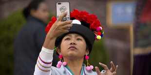 Eine Frau in folkloristischer Kleidung macht ein Selfie.