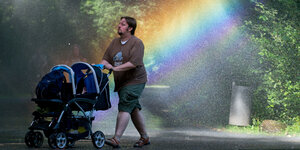 Mann mit Kinderwagen im Regenbogen