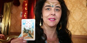 Eine Wahrsagerin auf dem Hamburger Dom hält eine Karte hoch