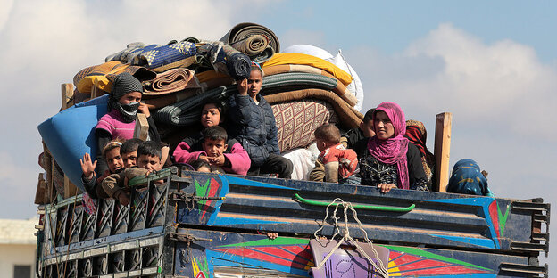 Eine vielköpfige Familie mit ihren Habseligkeiten auf der Ladefläche eines Lastwagens