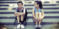 Ein Junge und ein Mädchen sitzen nebeneinander auf einer Treppe