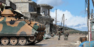 drei Soldaten laufen durch einen total zerstörten Straßenzug, im Vordergrung ein Panzer