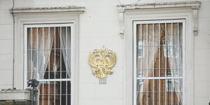 Eine Fassade mit vergitterten Fenstern und einem Wappen dazwischen