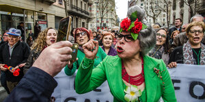 eine Demonstrantin mit erhobenem Zeigefinger blickt in eine Handykamera, im Hintergrund weitere DemonstrantInnen