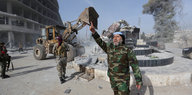 Ein Kämpfer posiert mit ausgestrecktem Zeigefinger vor einer zerstörten Statue