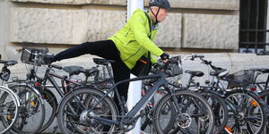 Jürgen Trittin in grüner Jacke steigt auf ein E-Bike