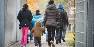 Menschen laufen einen vergitterten Weg in einer Rückführungseinrichtung entlang