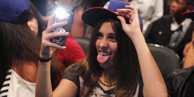 Eine junge Frau streckt die Zunge heraus und macht ein Selfie
