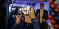 Mit einem Smartphone wird ein Foto von einem Trump-Plakat gemacht