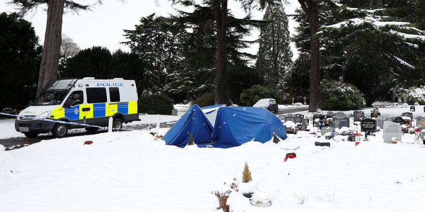 Ein Polizeiwagen neben einem verschneiten Friedhof