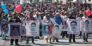 Menschen demonstrieren mit Plakaten in der Hand, darauf zu sehen sind die Gesichter der vermissten Studierenden