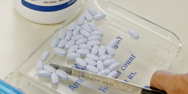 Ein Angestellter einer Apotheke hält ein Messer neben Tabletten, die das Opioid Hydrocodon und das Schmerzmittel Acetaminophen (Parazetamol) enthalten.