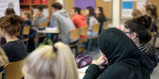 Schüler in einer Schulklasse mit dem Rücken zur Kamera