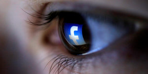 Eine Nahaufnahme eines Auges, in dem sich das Facebook-Symbol spiegelt