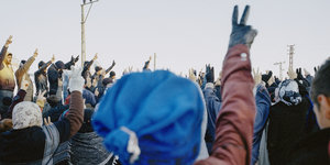 Eine Menschenmenge, aus der sich Hände, die das Victory-Zeichen formen, in die Höhe strecken