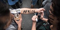 Jemand schreibt "Afrin" auf den Unterarm eines anderen