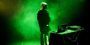 Eine Frau steht auf einer grün beleuchteten Bühne