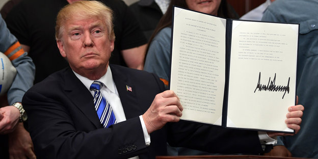 Donald Trump hält ein unterzeichnetes Dekret hoch
