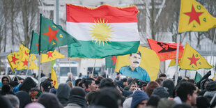 Bei einer Demo gegen die türkische Militäoffensive in Nordsyrien schwenken Menschen die kurdische Flagge und auch die verbotene Fahne des PKK-Führers Öcalan