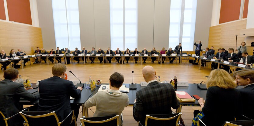 Viele Menschen in Anzügen sitzen in einem großen Kreis.