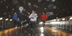 SportlerInnen laufen durch den Schneeregen