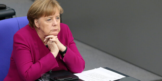 Merkel hat Hände gefaltet und schaut gelangweilt