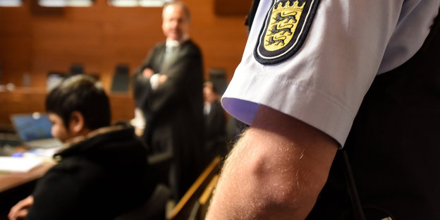 Ein Polizeibeamter steht hinter einem jungen Mann