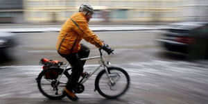 Ein Radfahrer fährt über eine zum Teil mit Schnee bedeckte Straße