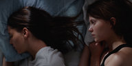 Zwei junge Frauen liegen nebeneinander in einem Bett