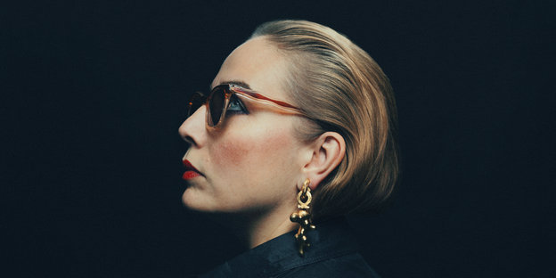Jenny Wilson im Profil mit Sonnenbrille vor schwarzem Hintergrund