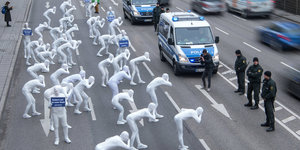 In weiß gekleidete Menschen stehen vor Polizisten