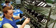 Eine Beschäftigte prüft Adidas Fußballschuhe