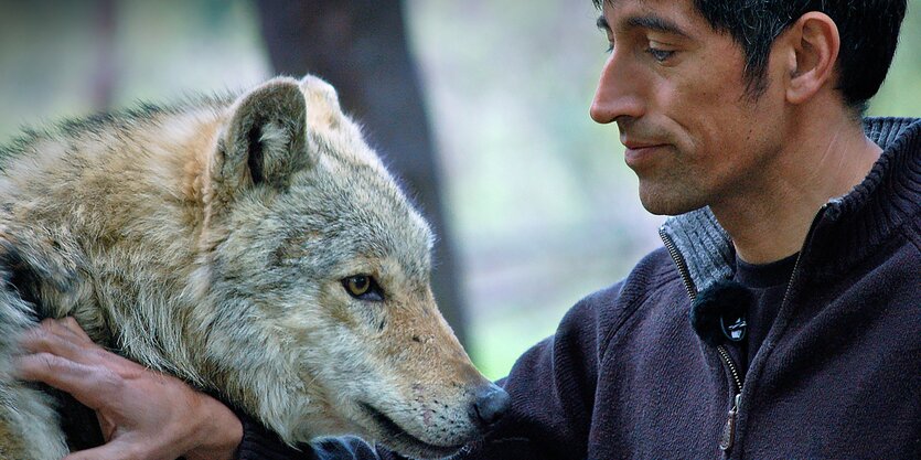 Ein Mann neben einem Wolf