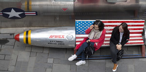 zwei Frauen sitzen auf einer mit einer US-Flagge dekorierten Bank in Form eines Sprengkopfes