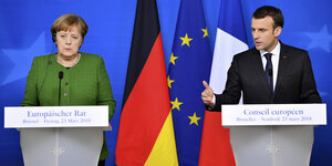Merkel und Macron stehen nebeneinander an Rednerpulten