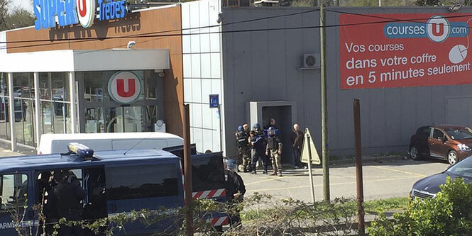 Polizisten stehen in einem kleinen Ort am Rande von Carcassonne auf der Straße