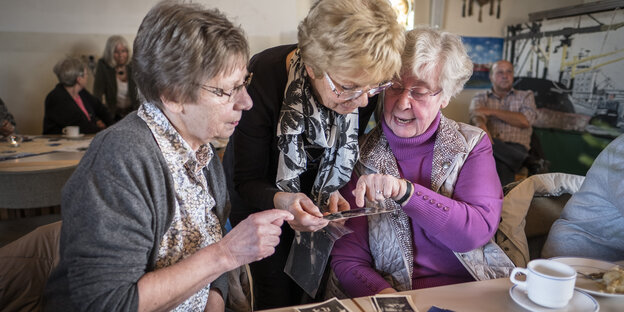 Drei ältere Frauen schauen Fotos an