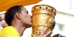 ein Mann küsst einen großen Pokal