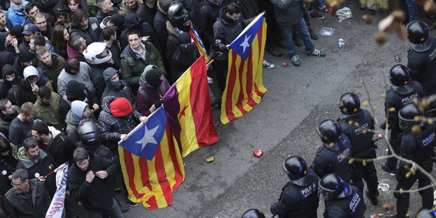 Menschen mit katalonischen Fahnen stehen Polizisten gegenüber