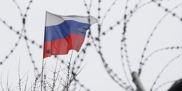 Eine russische Flagge hinter Stacheldraht