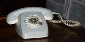 Ein altes Telefon mit Wählscheibe und geringeltem Kabel.
